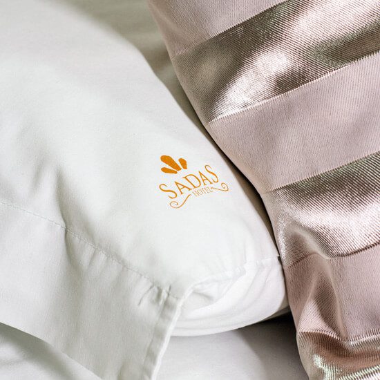 Uma imagem de uma roupa de cama limpa e bem cuidada com a logo do Sadas Hotel